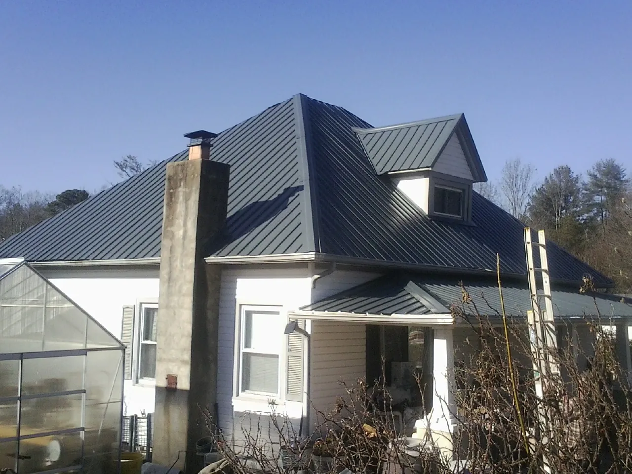 Dark blue standing seam metal roof on a white farmhouse with dormer — Slate & Tile Roof Repair by Roofing Brothers in San Bruno