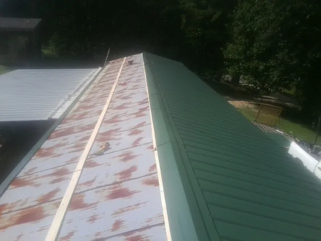Old rusted panels beside newly installed green metal roofing — Wind Damage Roof Repair by Roofing Brothers in San Bruno