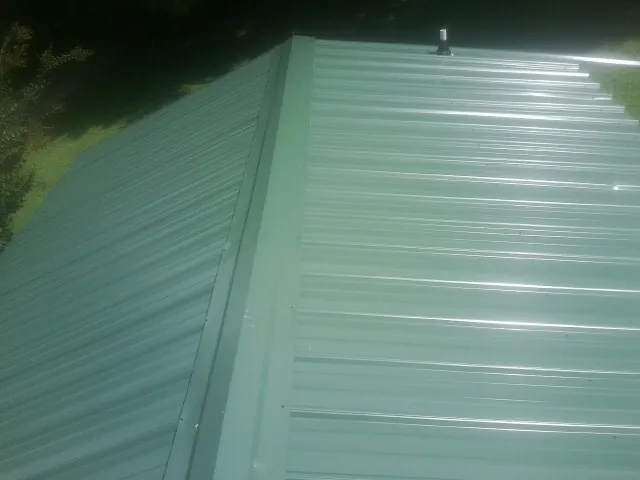 New green metal panels meeting at the ridge of a roof — Flat Roof Repair work by our crew in San Bruno