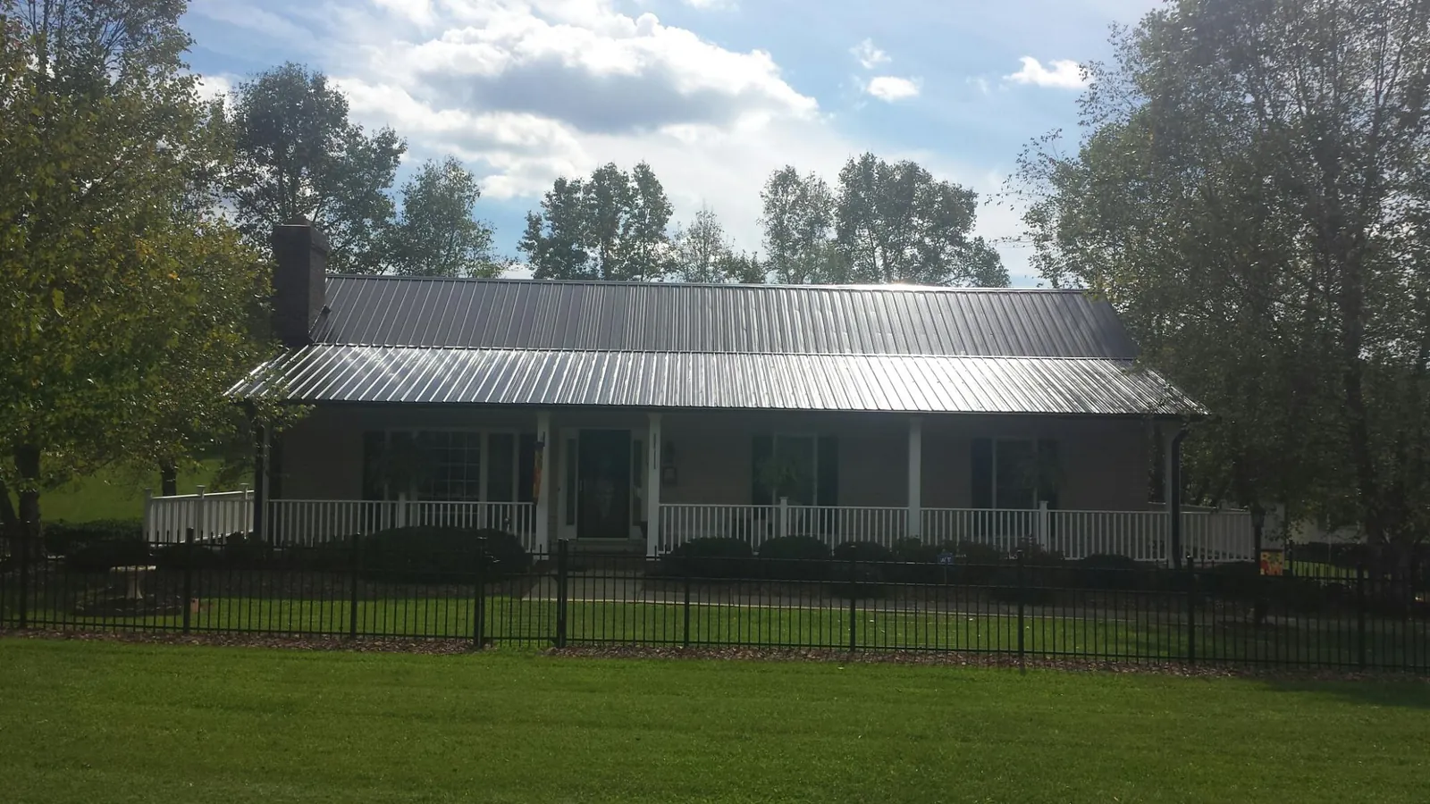 Gray metal roof on a brick ranch with a full width front porch — Gutter Guard Installation work by our crew in San Bruno