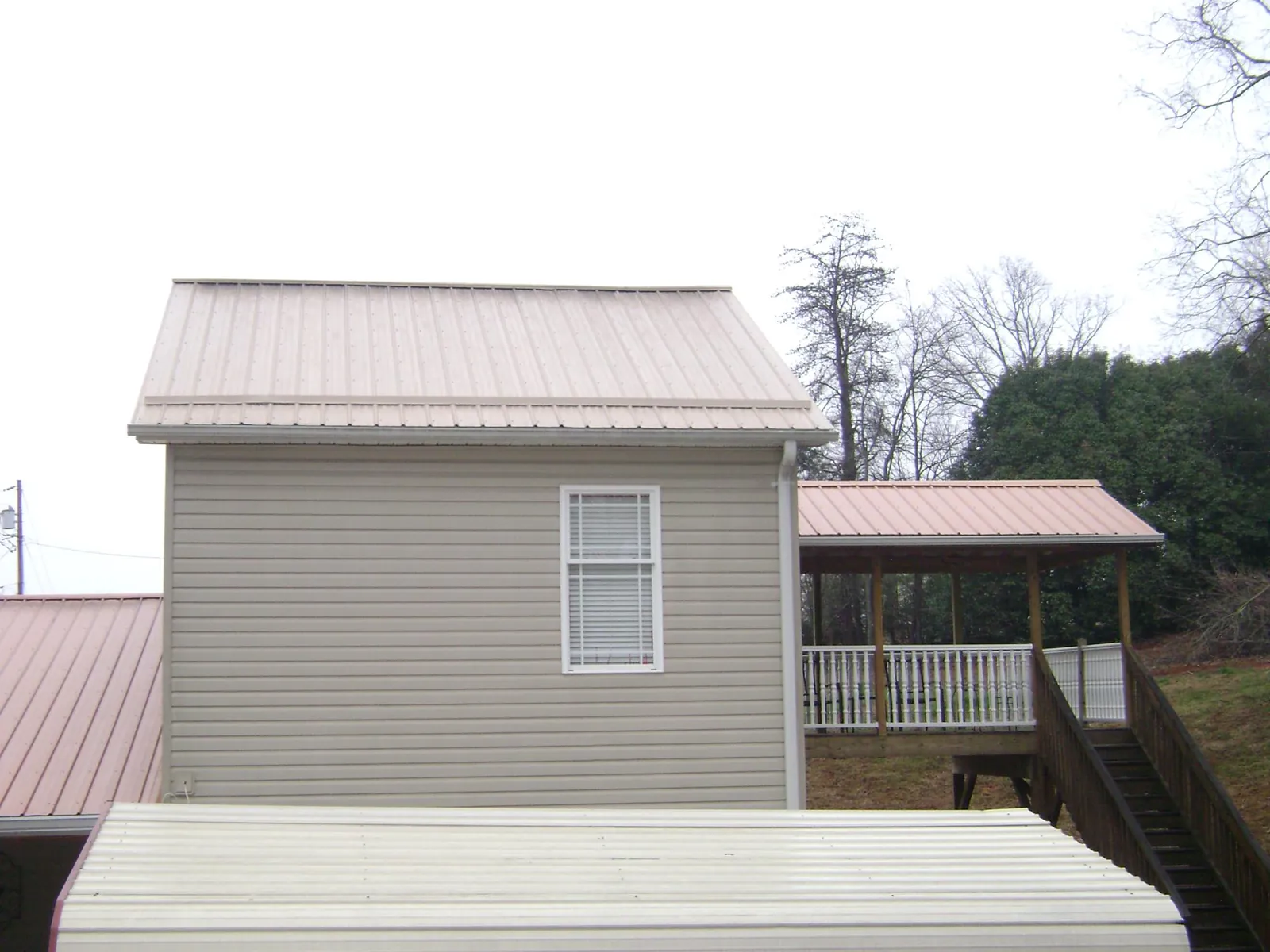 Tan metal roofs on a two story addition and attached porch, from a Roof Replacement job in San Bruno
