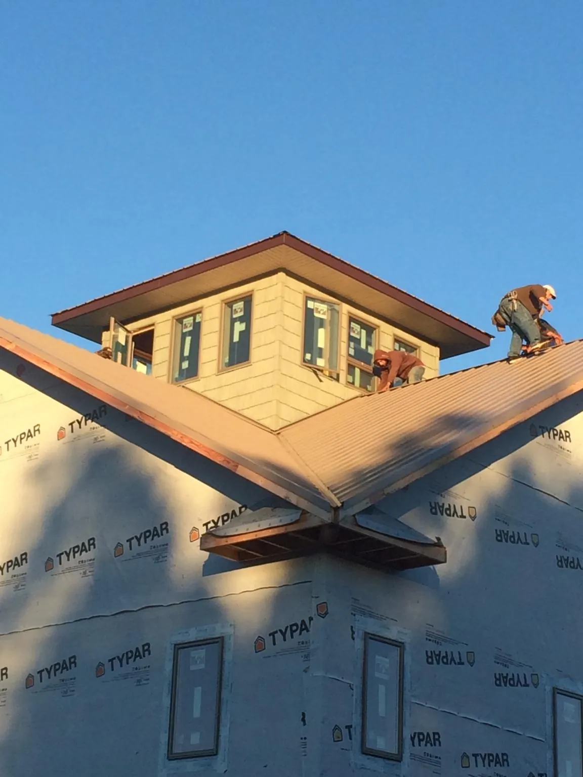 Roofers working around a rooftop cupola on a new metal roof at sunset — Roof Waterproofing in San Bruno by Roofing Brothers